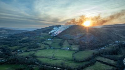 A grass fire at sunset on a hillside in the Brecon Beacons in South Wales GB