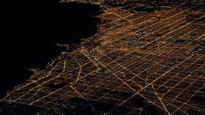 Aerial View Of Illuminated Cityscape By River At Night