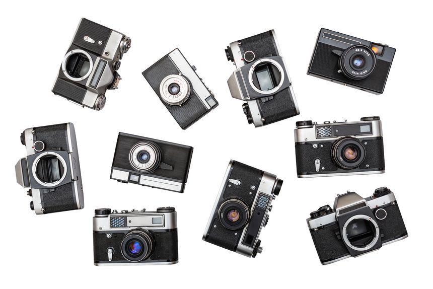Old used film cameras displayed in a creative arrangement on a plain white background, highlighting their retro design and vintage charm.