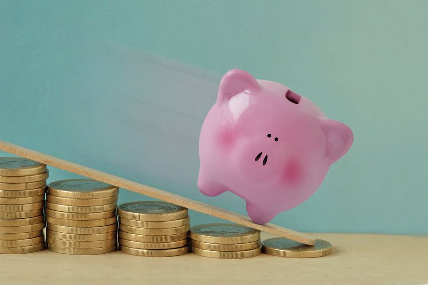 Piggy bank on decreasing piles of coins - Concept of finance and losing money