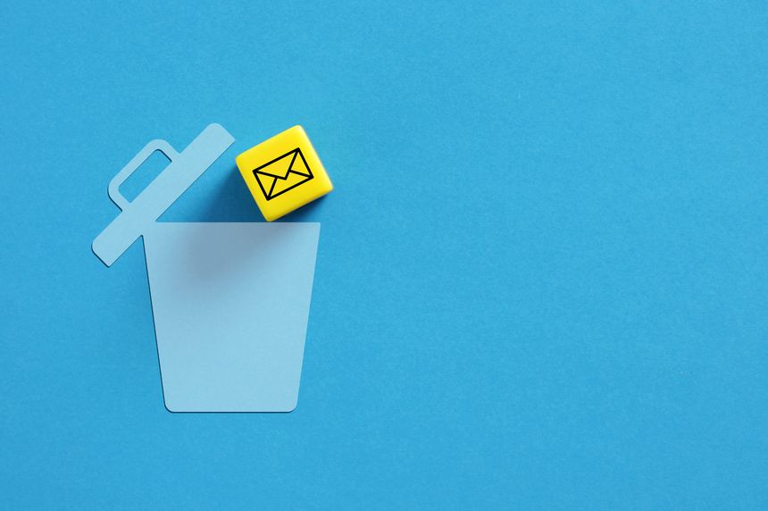 Yellow cube with an email symbol is falling into a blue trash can on a blue background. Depicting deleting emails. Spam mail.