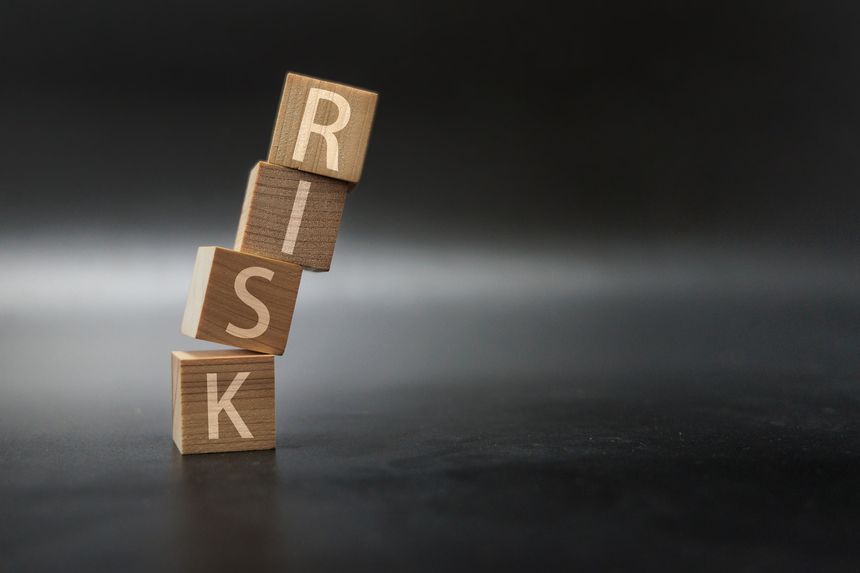Stacked wooden cubes spelling RISK falling over, symbolizing business uncertainty, danger, and risk assessment.