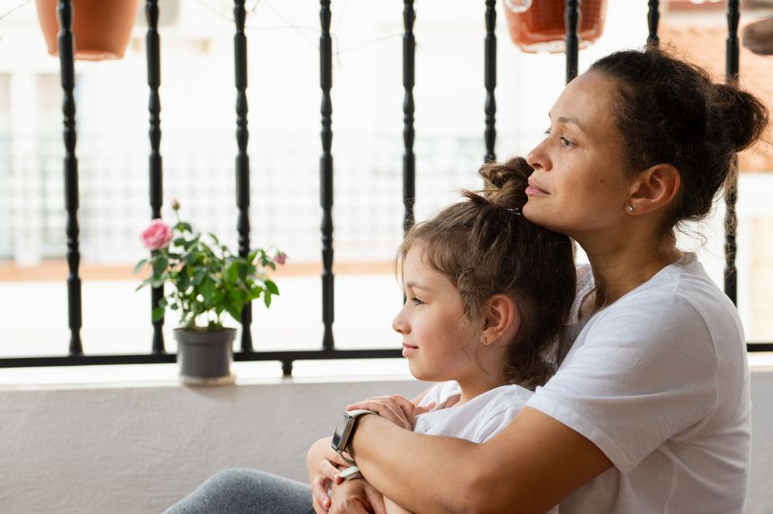A candid moment showing mother and daughter in an intimate embrace on a balcony, exuding warmth, love, and connection.