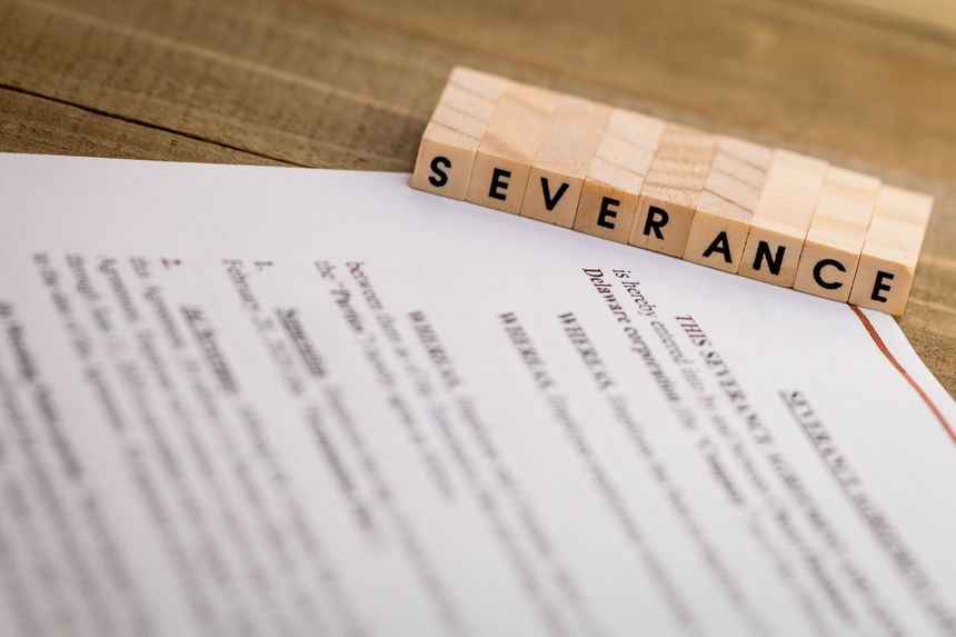 Severance Pay concept with agreement document on wooden board and SEVERANCE spelled out in wood blocks selective focus