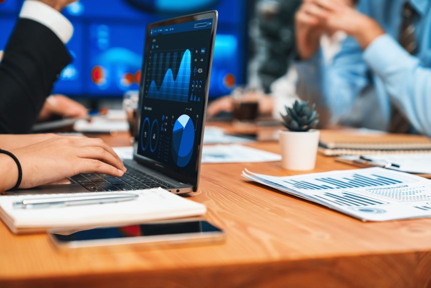 Closeup hand typing keyboard laptop with blurred background of business people using laptop to analyze financial data or data analysis display on screen background. Habiliment