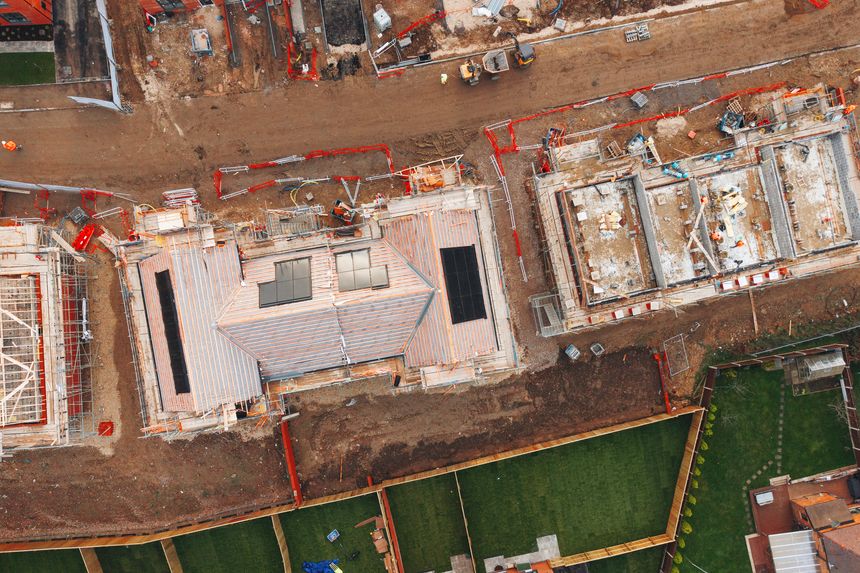 Aerial view from drone at new residential development featuring homes with solar panels integrated into the roofs for energy efficiency