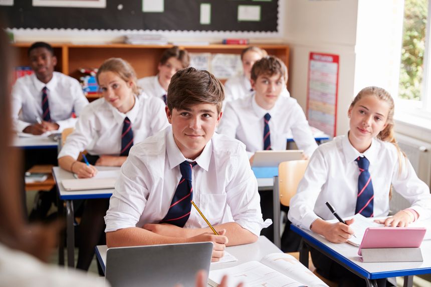 Students Listening To Female Teacher In Classroom