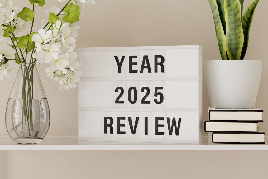 A lightbox displaying the words "Year 2025 Review" on a shelf with books and plants.