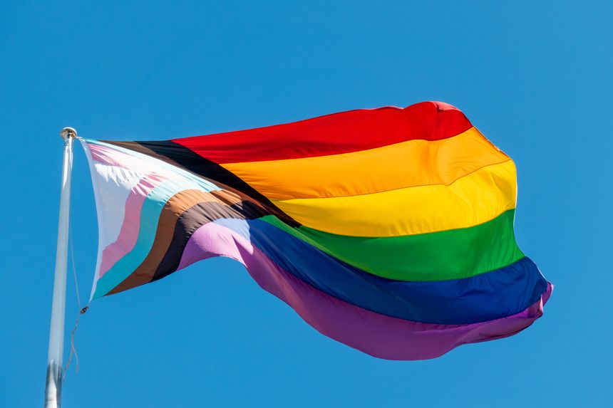 A large Progress Pride Flag flies on a flagpole in Taylor Square, Oxford Street, Darlinghurst, Sydney.  This image was taken on a sunny and windy afternoon on 5 April 2025.