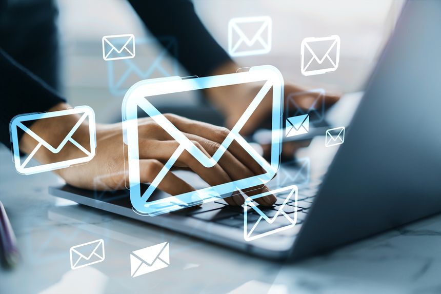 Person typing on laptop with glowing email icons overlaid, modern style, on blurred desktop background, concept of digital communication and messaging