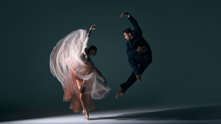 Ballet couple moving in synchronized dramatic jump with flowing dress motion. Concept of energy, passion, performing arts, fluid choreography, emotional harmony and cultural expression.