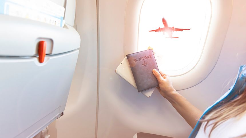 Young hipster tourist with Blue passport  near a window which already to travel in the airplane-Travel concept