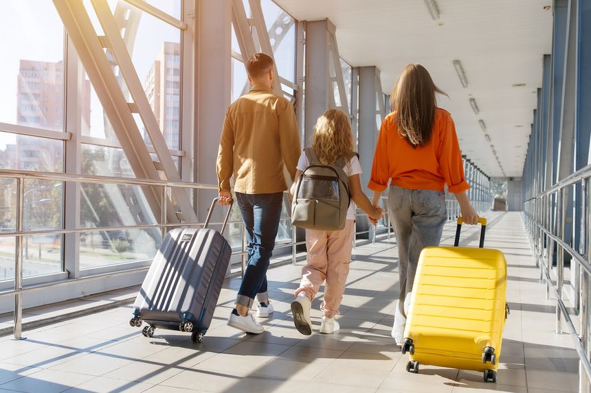 European family walking together at airport corridor with luggage, holding hands and smiling, showing cheerful lifestyle, bonding, unity and joyful holiday departure