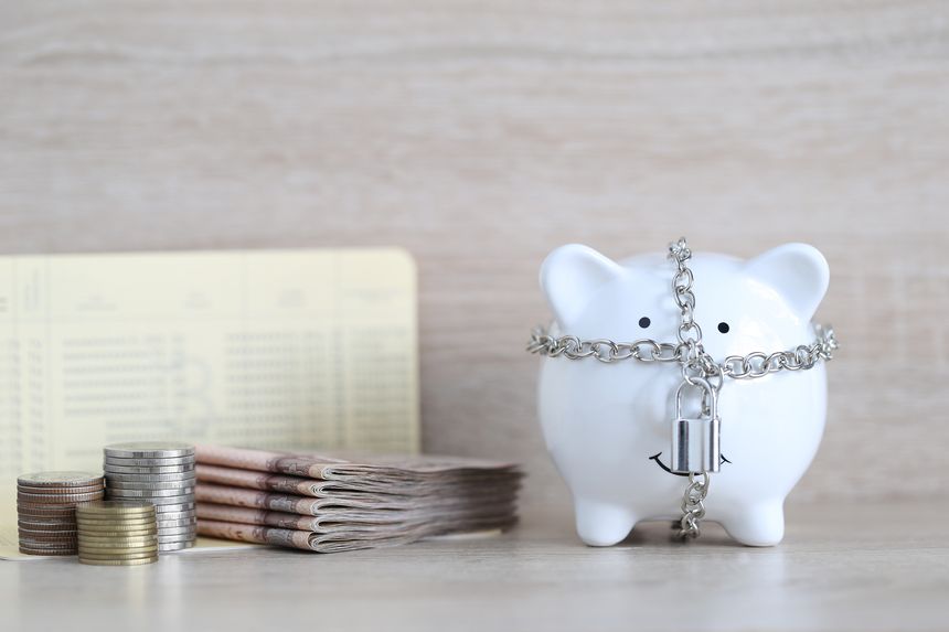 Blocked accounts,Piggy bank with padlock and banknotes on wooden background,Account passbooks were locked or Account frozen concept