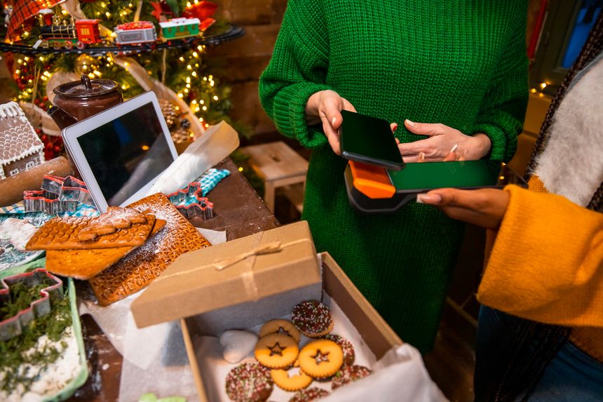 Female customer making contactless payment with smartphone in bakery store. Close up