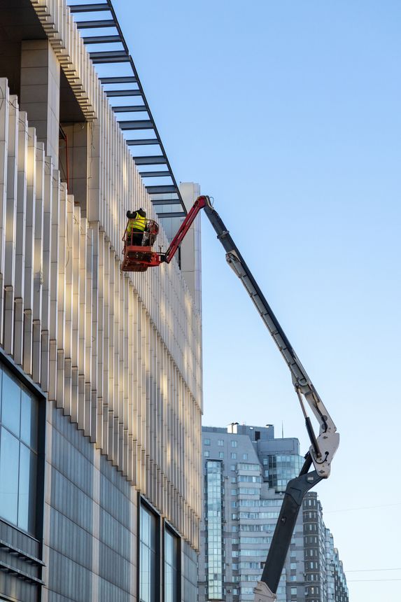 Construction crews and installers of high-rise buildings install fittings or lay electrical wiring. they work at a height in a lifting bucket. Construction and glazing of a new residential building.