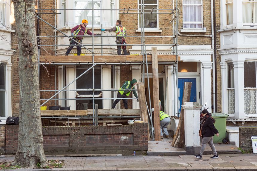 London, UK - May 4, 2021: Four workers collaborate to build a scaffold during the refurbishment of a residential premises in London