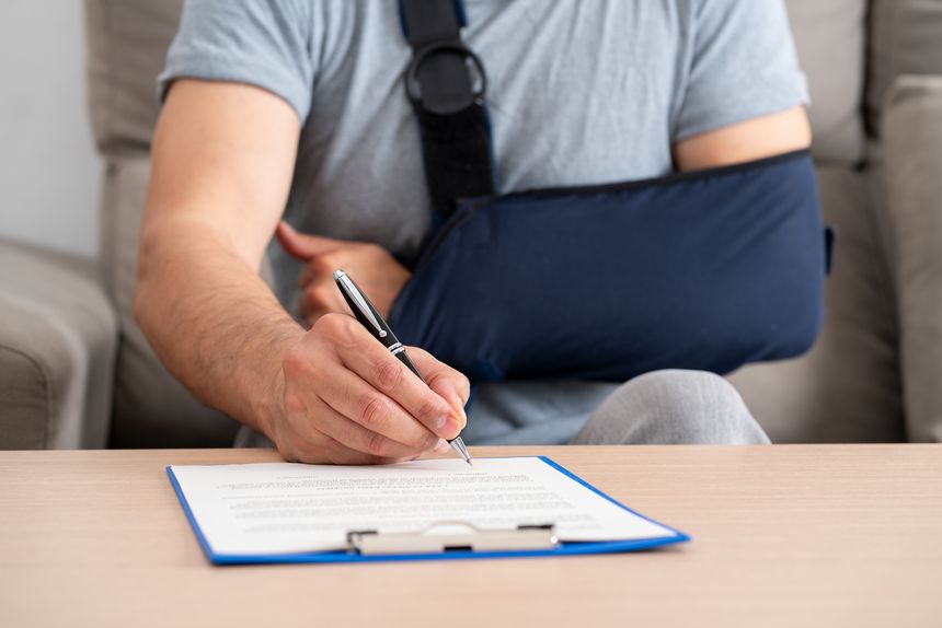Front view of a handicapped man with sling signing contract at home