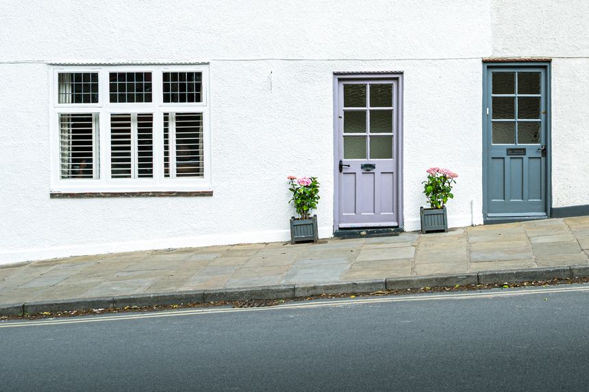 Abstract view of a pair of terraced houses seen up a hilly road in England. The road and pavement is partially hazardous in poor weather.