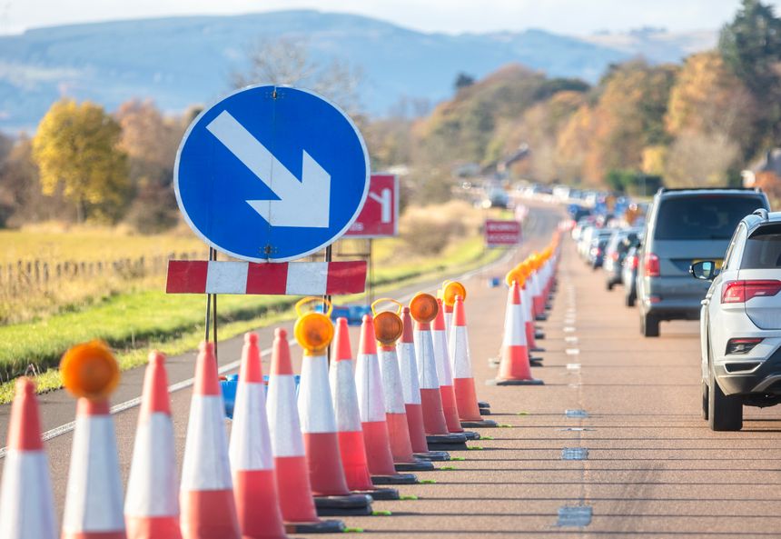 Traffic jam road works congestion with rows of cars and traffic cones on highway or motorway in rush hour