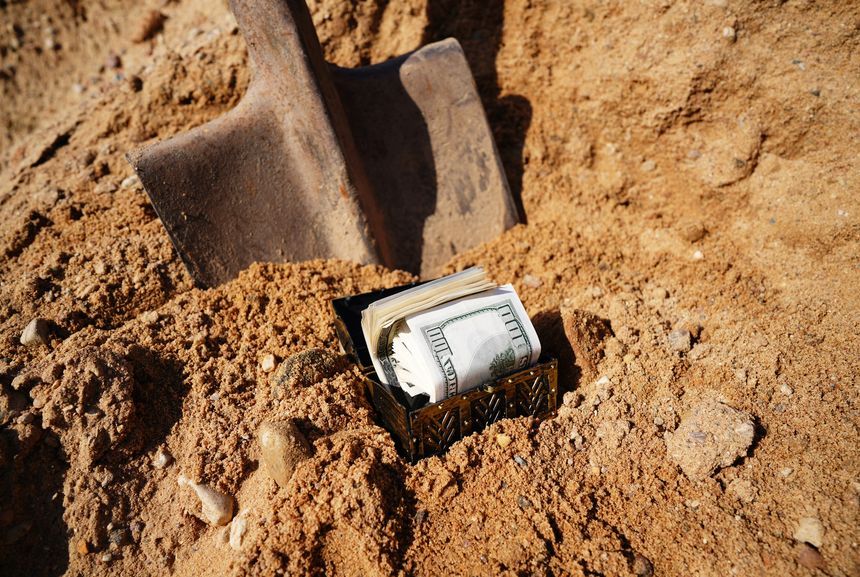 Treasure Chest Buried in the Sand With Dollars Cash Shovel. Dig treasure. Bury money. Digging Treasure box in soil use shovel. Digs dorrars note from ground. Treasure hunter concept. Hide money.