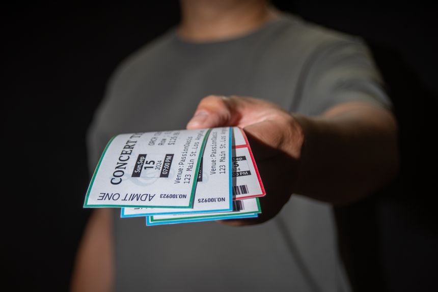 A hand extracts three concert tickets from a pocket, a common tactic used in ticket scalping