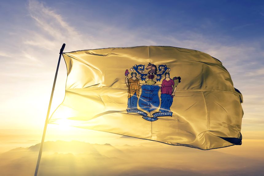 New Jersey state of United States flag on flagpole textile cloth fabric waving on the top sunrise mist fog