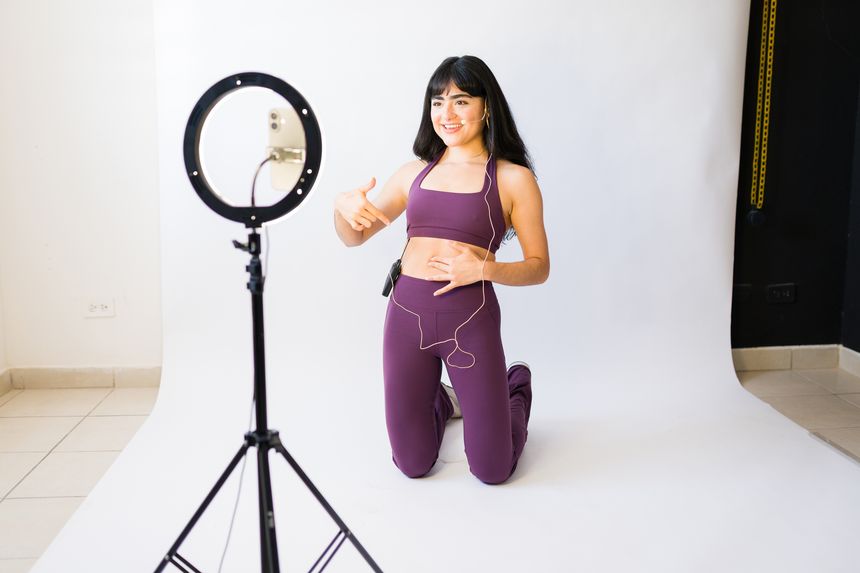 Female coach recording online workout tutorial, demonstrating fitness exercises for remote students and social media followers