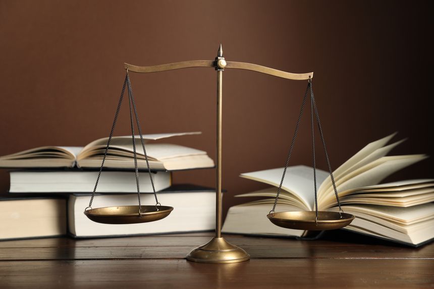 Scales of justice and books on wooden table