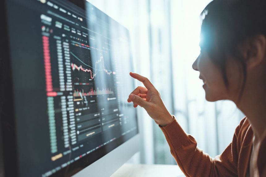 Closeup - Woman is checking Bitcoin price chart on digital exchange on computer screen, cryptocurrency future price action prediction.