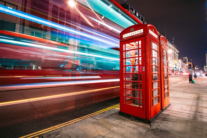 Light trails of a double decker bus next to the iconic telephone booth in London