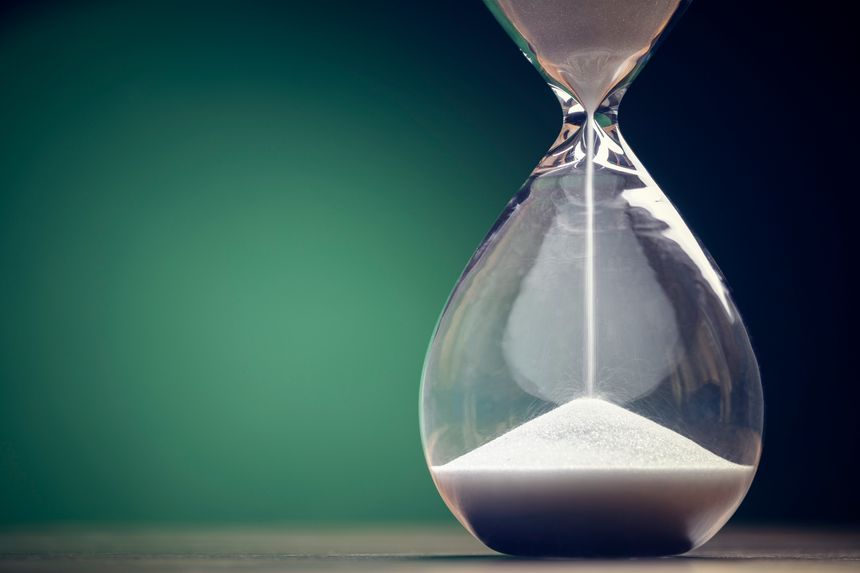 Hourglass time passing green background concept for business deadline, urgency and running out of time