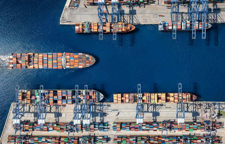 Aerial top down view of a large container cargo ship terminal harbor with loading activity and vessel traffic