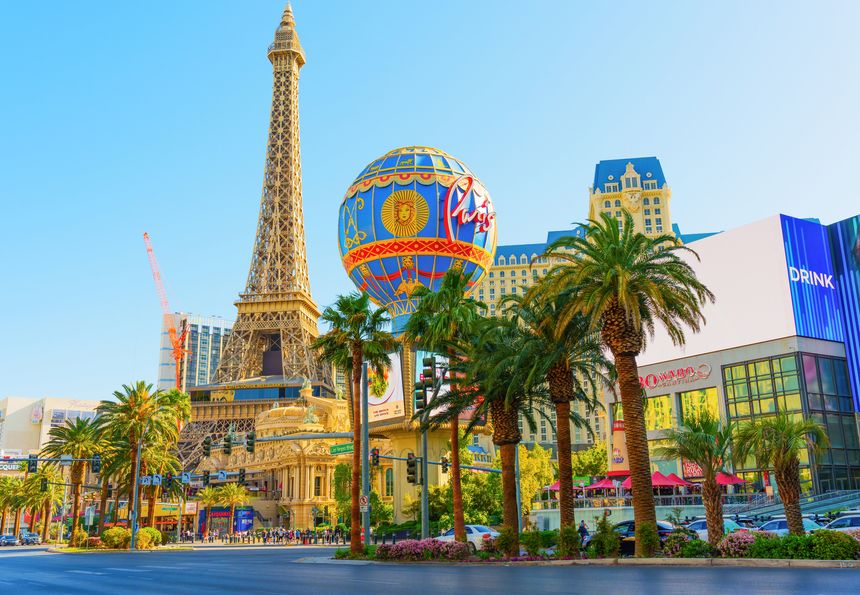 Las Vegas, Nevada - April 13, 2024: Detailed view of the Paris Las Vegas Hotel showcasing the Eiffel Tower and colorful hot air balloon, surrounded by lush palm trees.