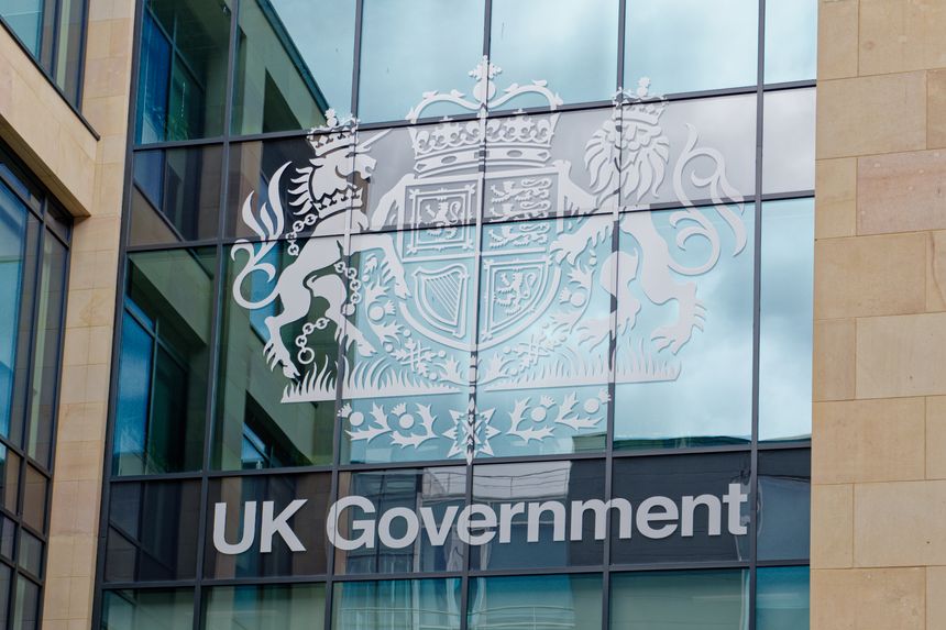 Modern UK government building in Edinburgh. Large text sign and coat of arms on glass windows with reflection on a cloudy day. Edinburgh, UK, 05.03.2025