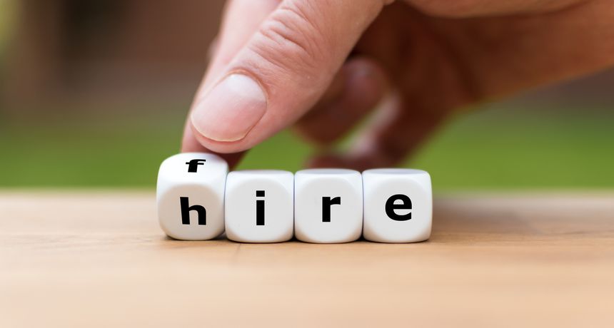 Hand is turning a dice and changes the word fire to hire