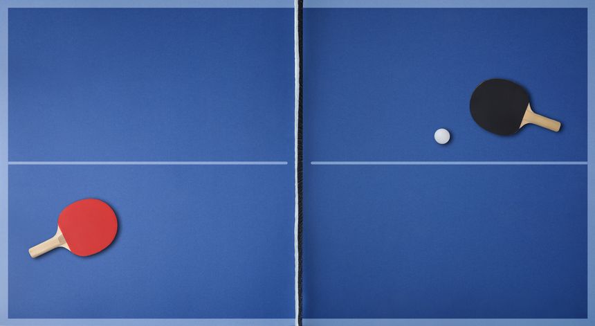 Top view of professional blue ping pong playing surface with paddles on each side and ball. Top view.