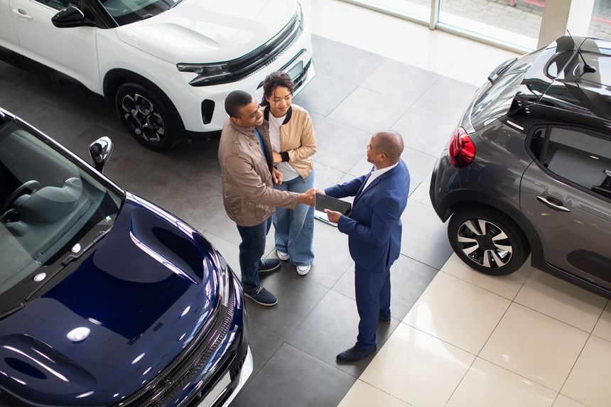 African American couple shaking hands with dealer in showroom, celebrating agreement on new car purchase, lifestyle and transport concept of business and success
