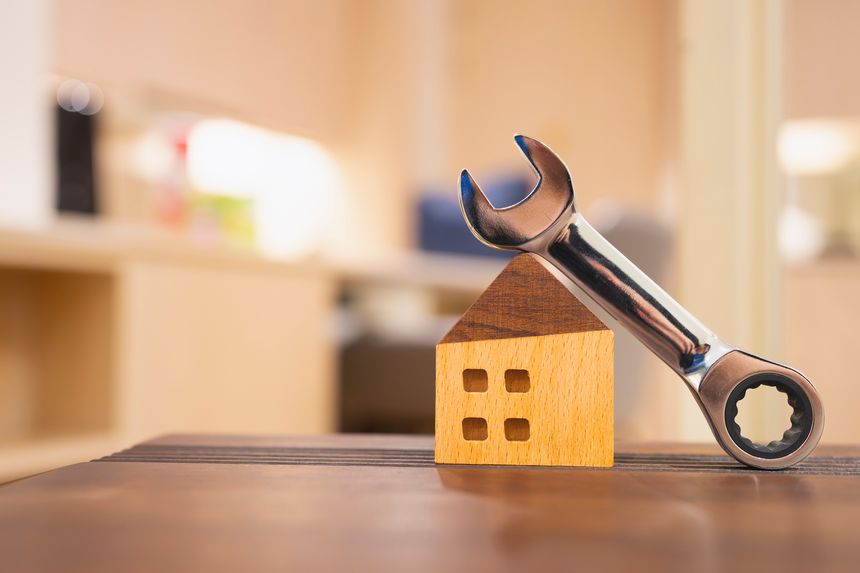 Wrench leaning against wooden house model, symbolizing home repair, maintenance, renovation, property care, or real estate service. Ideal for construction, housing, and handyman business concepts.