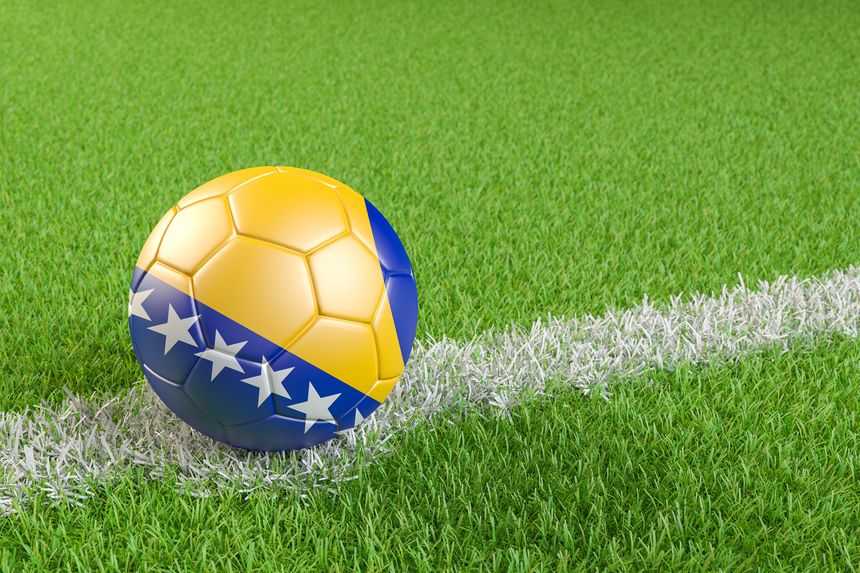 Football / soccer ball with a flag overlay of Bosnia and Herzegovina on a football pitch background. International match and national team of Bosnia Herzegovina concept