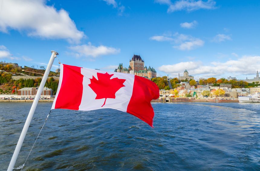 Canadian flag with autumn view of Old Quebec City waterfront and Upper Town from Saint-Lawrence River in Quebec, Canada