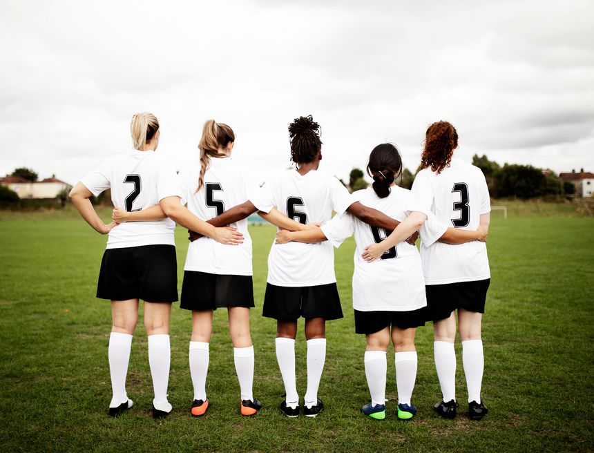 Female soccer players huddling and standing together