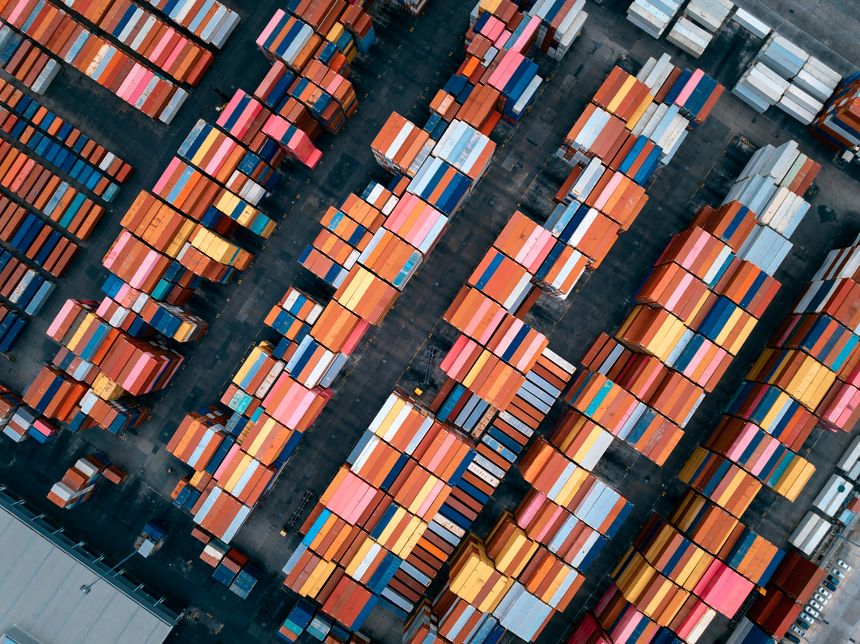 warehouses, containers goods stacked, lined up to wait for distribution to consumers and dealers by ship and truck transportation, industrial, transportation and financial business concept, aerial top view.