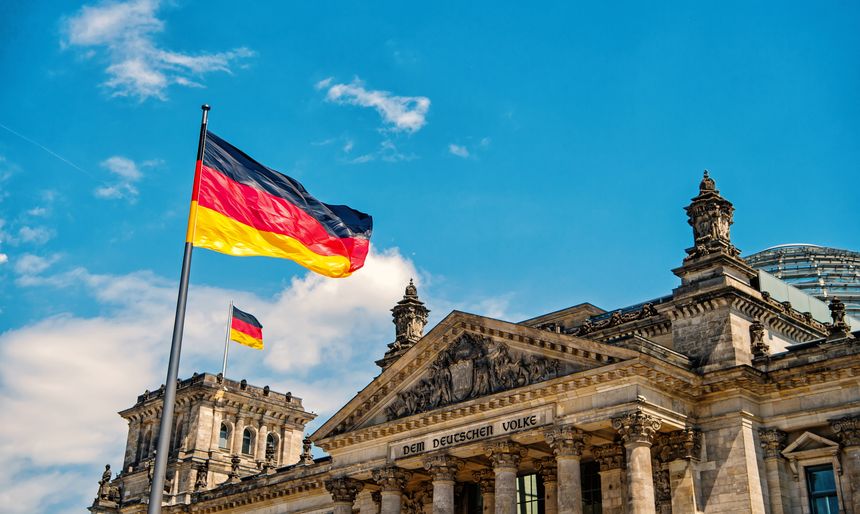 German flags waving in the wind at famous Reichstag building, seat of the German Parliament Deutscher Bundestag , on a sunny day with blue sky and clouds, central Berlin Mitte district, Germany