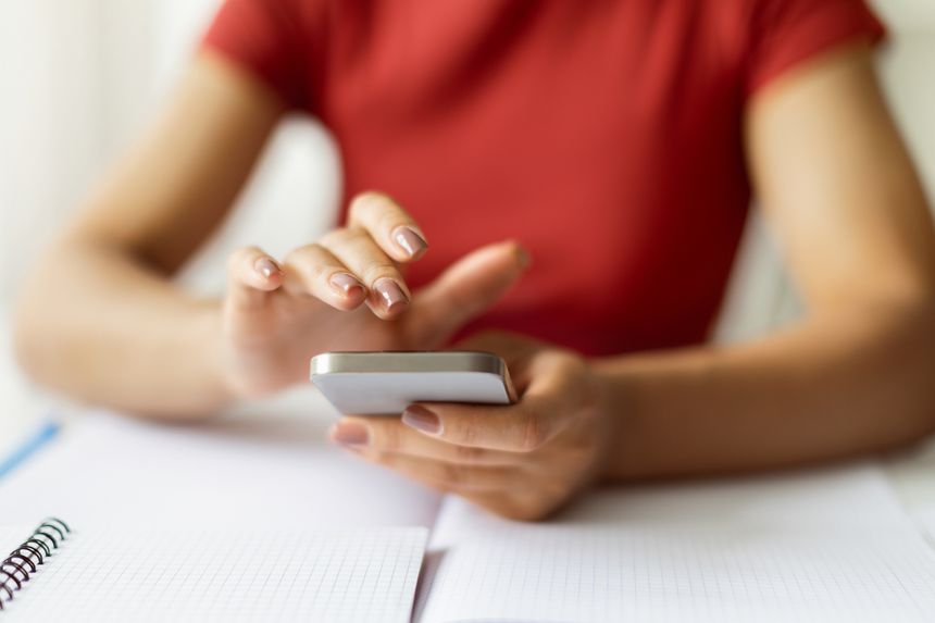 Closeup Shot Of Young Black Woman Sitting At Desk And Using Smartphone, Unrecognizable African American Female Holding Mobile Phone In Hands, Messaging Or Browsing Application, Cropped Image