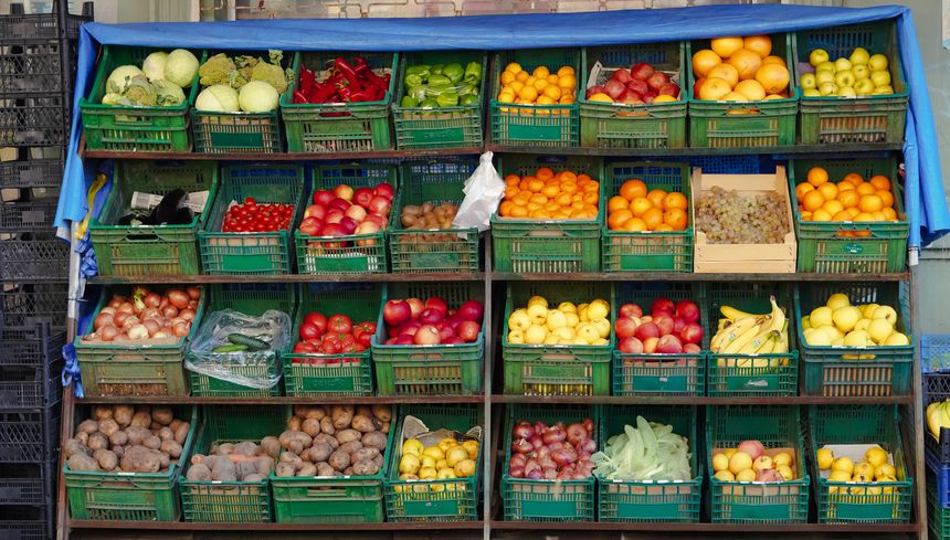 Colorful assortment of fruits and vegetables in green baskets at an outdoor market stall