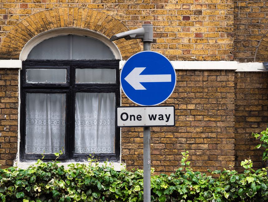 One way traffic sign in front of brick building with ivy in London