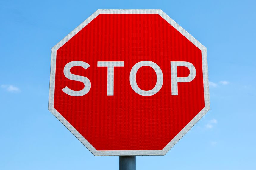 Close-up of a STOP sign with a blue sky behind.