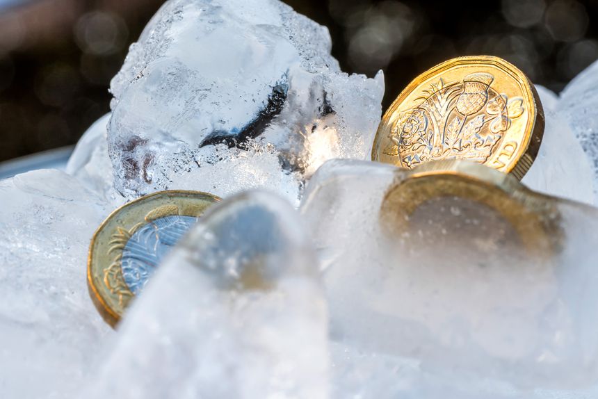 Frozen New British one pound sterling coin up close macro inside ice cubes.