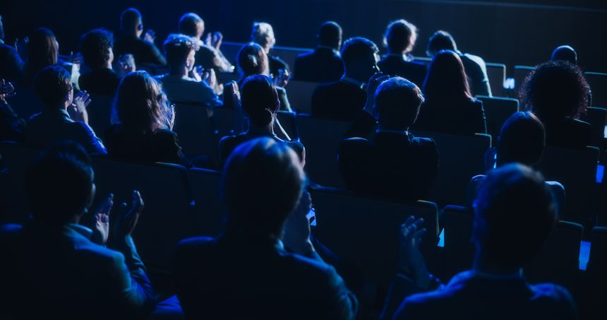 Crowd of Smart Tech People Applauding in Dark Conference Hall During a Motivational Keynote Presentation. Business Technology Summit Auditorium Room Full of Delegates. Footage from Behind.